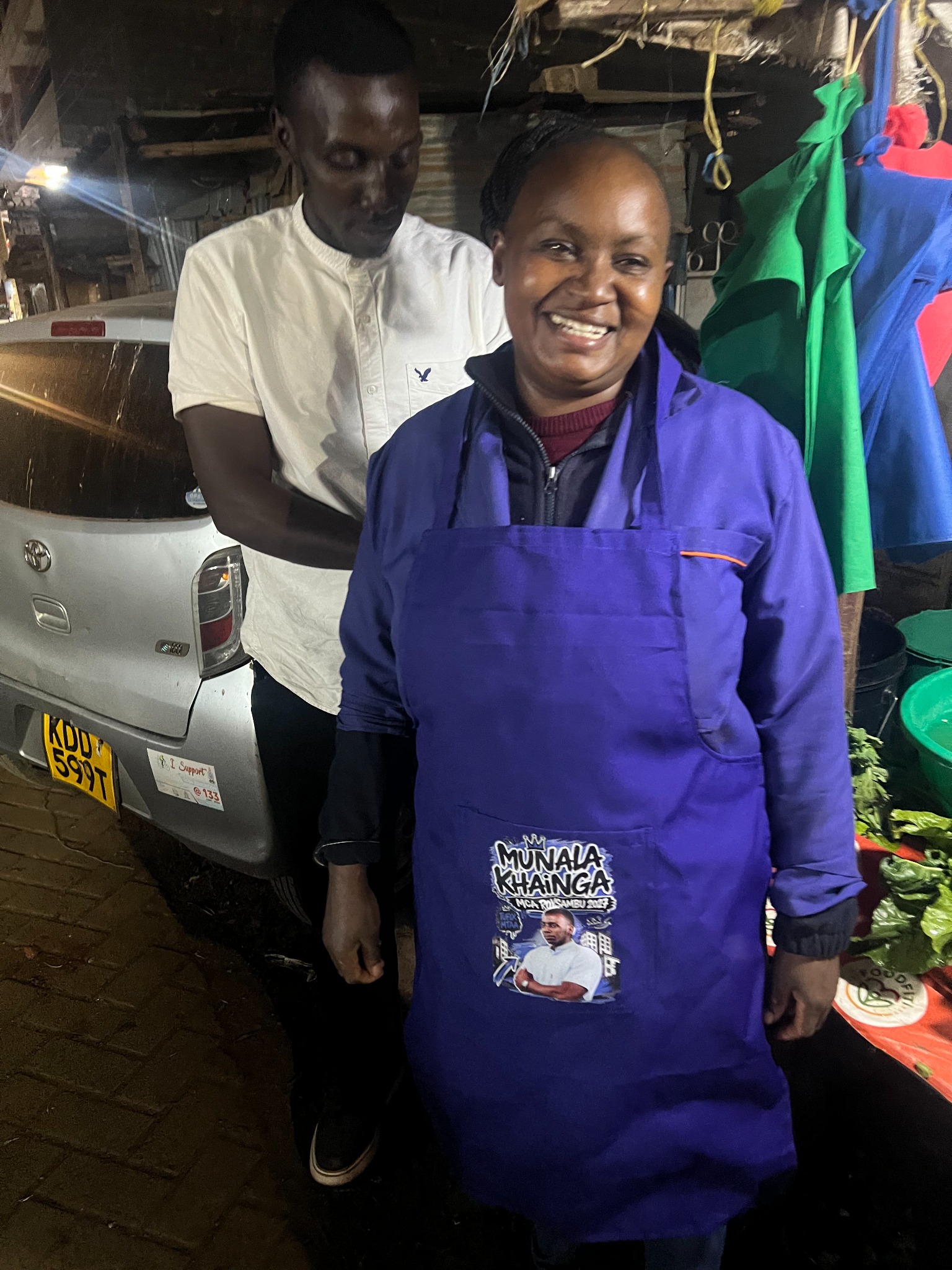 Munala presenting a branded work apron to a mama mboga in Roysambu